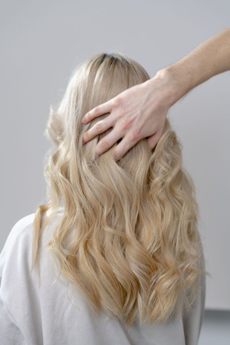 A stylist's hand resting on long, freshly styled hair