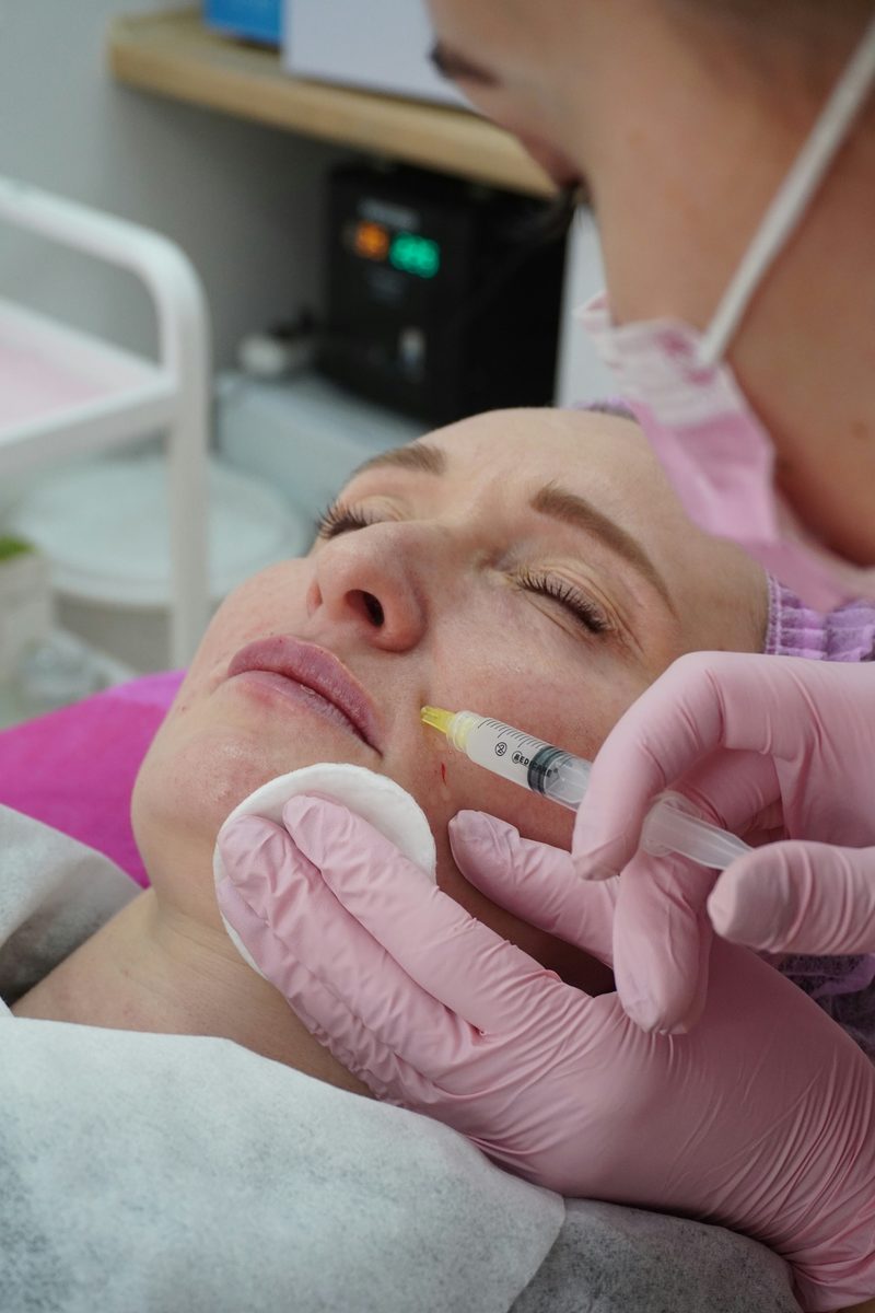 A practitioner administering a dermal filler injection to a client's cheek