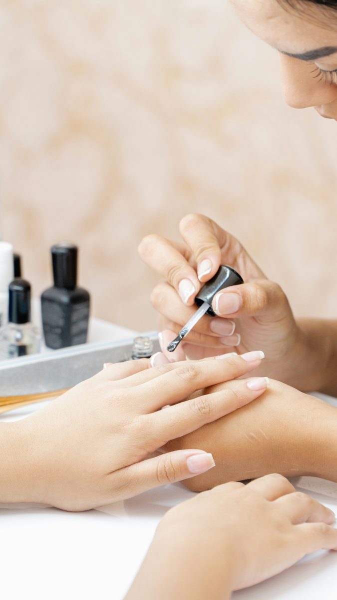 A nail technician applying polish during a manicure