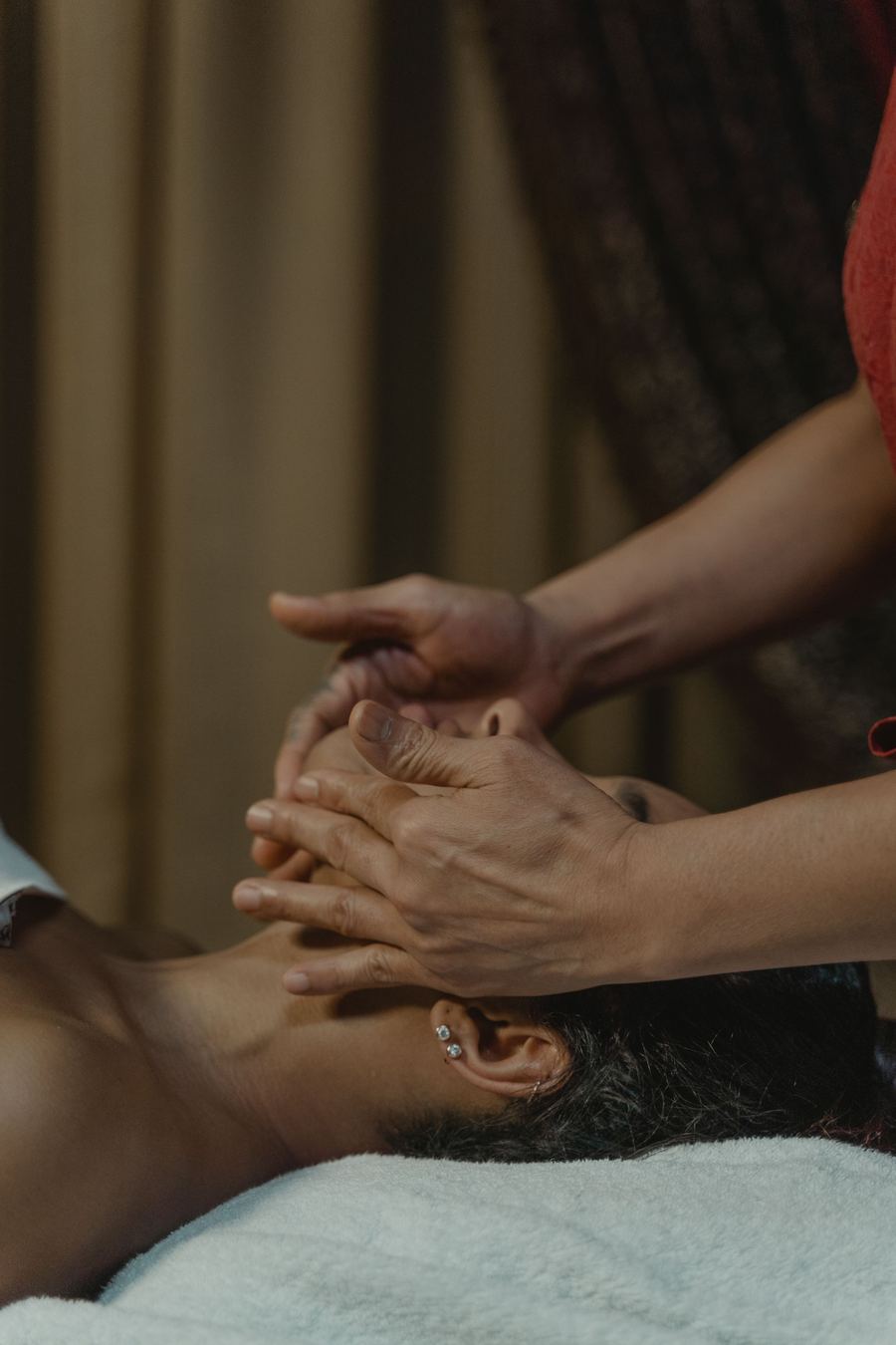 A practitioner performing a slow, precise facial treatment on a client in a dimly lit treatment room